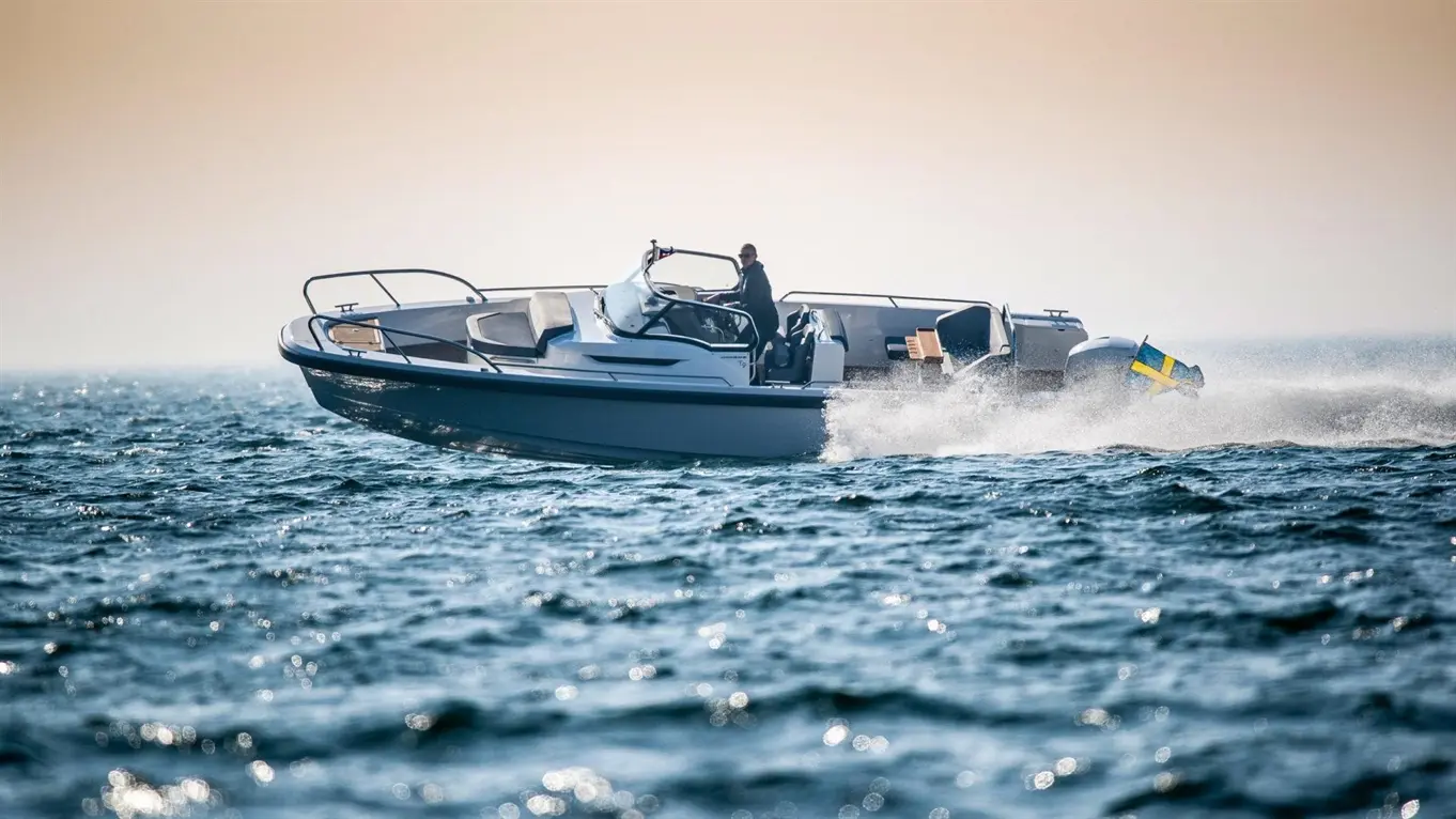 A speedboat with a driver cuts through shimmering water, displaying a Swedish flag as it moves swiftly across the surface.
